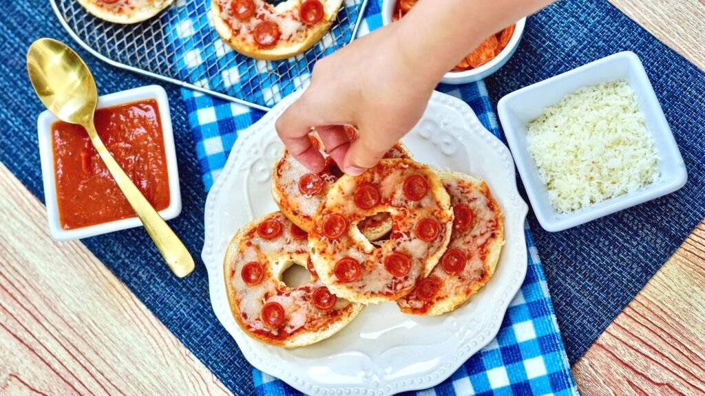 Hand reaching down onto a plate of air fryer mini pizza dinner