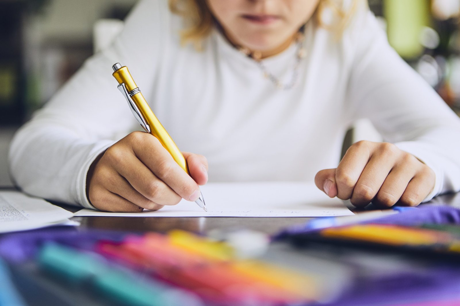 Young girl doing homework at a table holding a pencil