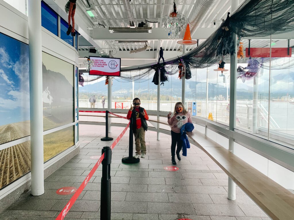 Kids in outdoor queue for Flyover Canada with Halloween decorations