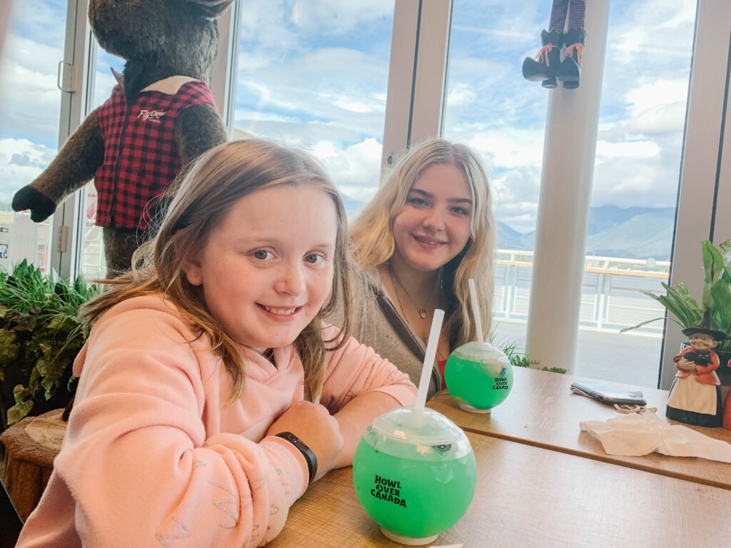 Two blonde girls enjoying Howlover Canada Flyover Canada green globe drinks at the Flying Whale Cafe