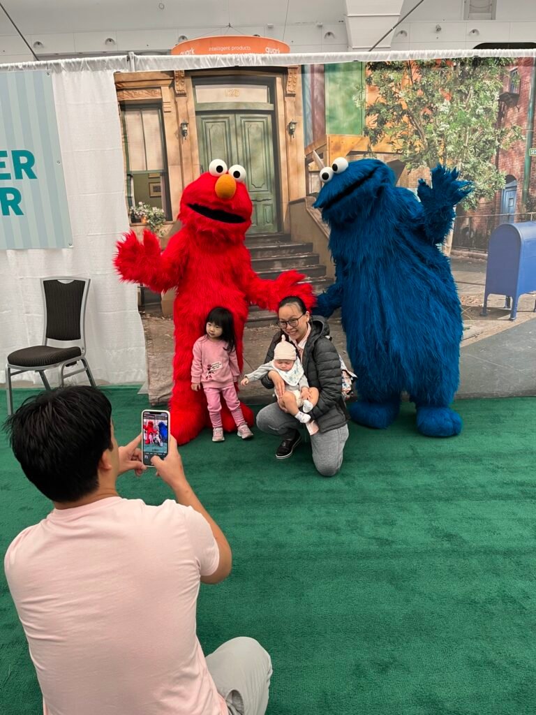 The Baby Show Elmo & Cookie Monster photo opportunity wall with parents taking photos of their children