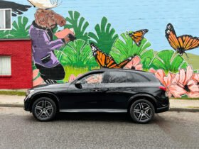 Black Mercedes 2023 GLC 300 in front of painted wall with butterflies